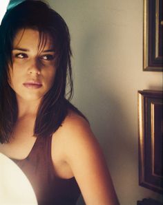 a woman is sitting in front of a mirror and looking at the camera with an intense look on her face