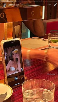 a cell phone sitting on top of a wooden table next to a glass filled with water