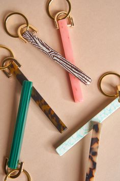 four different types of keychains on a table next to some pens and pencils