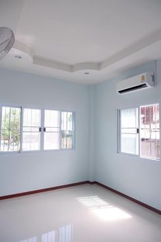 an empty room with two windows and a fan