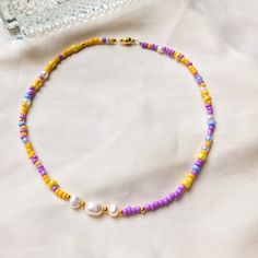 Summer Pearls necklace/ choker with purple & yellow beads This beautiful and stylish pearl choker is about 35 cm in length. To be creative and explore the versatility of the necklace, you can also wear it as a bracelet!  Made with love - Made in Berlin Freshwater pearls are also a natural product, and the shape and colour vary slightly. The pearl choker is made with jewelry gold wire. Total length: 35 cm  Seed beads: 3-4 mm, also gold-plated Diameter of freshwater pearls: 3-4 mm & 6mm  --------- Handmade Yellow Pearl Necklaces, Yellow Pearl Beaded Necklaces As Gift, Yellow Pearl Necklaces With Round Beads, Yellow Beaded Pearl Necklace, Purple Choker With Colorful Beads For Gift, Yellow Beaded Pearl Necklace As Gift, Yellow Beaded Pearl Necklace Gift, Trendy Purple Round Bead Necklaces, Trendy Purple Round Bead Necklace