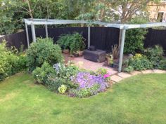 a garden with lots of plants and flowers in it's center area next to a black fence