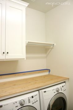 a washer and dryer in a small room with white cabinets on the wall