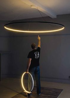 a man standing in front of a circular light fixture that is suspended from the ceiling