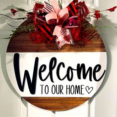 a welcome sign hanging on the front door to someone's home with red and black bows