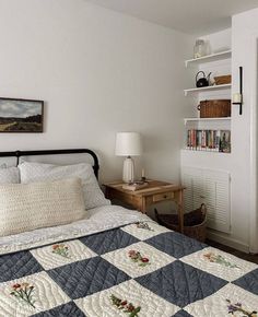 a bedroom with a quilted bedspread on the bed and bookshelves