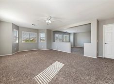 an empty living room with carpeted floors and windows