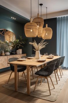 a dining room table with chairs and lights hanging from it's ceiling, in front of a blue wall