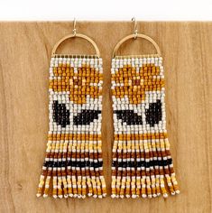 two pairs of beaded earrings on a wooden surface with beads hanging from the hoop