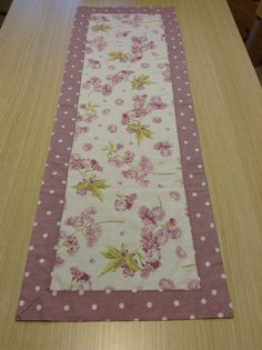 a table runner with pink flowers and polka dots on the edge, sitting on top of a wooden table