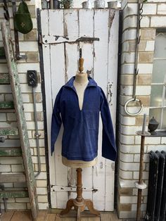 a mannequin is standing in front of an old door with a blue jacket on it