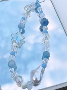 a close up of a necklace on a window sill with sky in the background