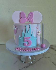 a birthday cake with pink and blue frosting on a table next to a wall