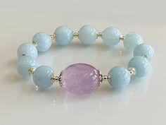 "💎 Natural Aquamarine and Lavender Amethyst Bracelet with 925 Sterling Silver, March Birthstone, February Birthstone, Stretch Bracelet. This beautiful all-natural gemstone bracelet features 12mm soft blue genuine aquamarine beads and gorgeously accented with large natural lavender amethyst stone as a center piece. Made with high-quality elastic stretch for easy on and off. ** Please read \"Wrist Measurement\" instructions below before placing your order ** WRIST MEASUREMENT How To Select the Ri Gemstone Combinations, Bracelets Beads, Lavender Amethyst, Ruby Bracelet, Aquamarine Beads, Natural Stone Bracelets, March Birthstone, Birthstone Bracelets, Amethyst Bracelet