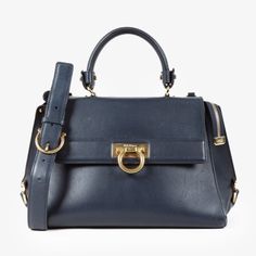 The Medium Sofia Top Handle Bag From Salvatore Ferragamo Is Expertly Crafted From Smooth Leather In Navy With Gold-Tone Hardware. Made In Italy, This Elegant Satchel Features Protective Base Studs, A Zipper Compartment At The Back, And The Signature Gancini Fastening At The Front. Its Flap Opens To A Main Zipper Compartment Lined In Matching Navy Leather And Equipped With Two Flat Pockets. This Ferragamo Bag Can Be Carried By Its Top Quilted Handle Or On The Shoulder By Its Detachable Leather Strap. Condition: Very Good; Faint Slouching, Moderate Markings On Exterior Leather, Minor Wear On Hardware, Visible Scuffings On Sides, No Inclusions Approximate Measurements: Height: 8” (20.5 Cm Blue Calf Leather Shoulder Bag With Detachable Strap, Blue Calf Leather Bag With Gold-tone Hardware, Luxury Blue Calf Leather Bag, Chic Blue Calf Leather Bag, Blue Calf Leather Bag With Detachable Strap, Classic Blue Calf Leather Shoulder Bag, Timeless Blue Bag With Top Handle, Luxury Blue Satchel With Palladium Hardware, Classic Blue Satchel With Branded Hardware