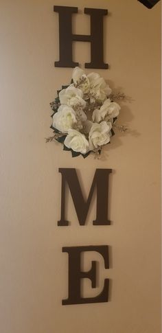 the word home is made out of metal letters with flowers on top and below it