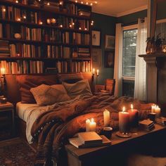 candles are lit in front of a bed with bookshelves and blankets on it