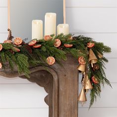 a decorated mantle with oranges, pine cones and bells