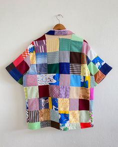 a colorful patchwork shirt hanging on a wall