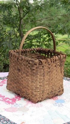 a wicker basket sitting on top of a quilted tablecloth with trees in the background