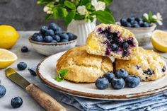 blueberry muffins on a plate with lemons and flowers in the background