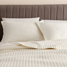 a bed with white sheets and pillows on it