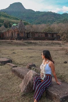 a woman sitting on top of a stone bench