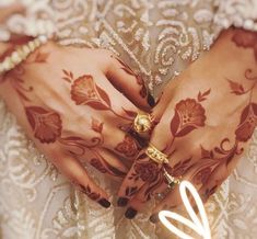 the hands of a woman with henna on their palms are decorated with gold jewelry