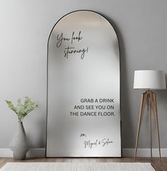 a large mirror sitting on top of a wooden floor next to a vase with flowers