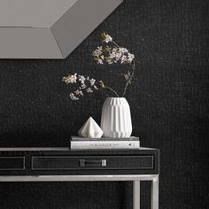 a vase with flowers on top of a table in front of a black and white wall