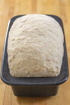 a loaf of bread sitting on top of a black pan next to a wooden table