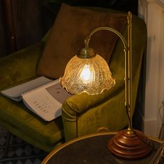 a green chair with a lamp on it in front of a book and a couch