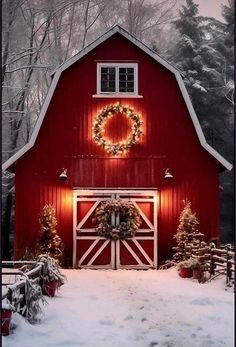 a red barn with a wreath on the door and lights hanging from it's windows