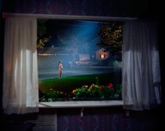 a person standing in front of a window at night with the light shining on them