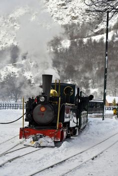 a steam engine train traveling down tracks in the snow