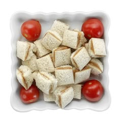 a white bowl filled with cut up bread and cherry tomatoes on top of each other