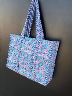 a blue and pink bag hanging on the wall next to a black wall with a white stripe