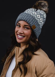 Grey & cream patterned knit hat. Natural faux fur pom accent - fleece lined 100% Acrylic. Winter Hats With Faux Fur Trim, Beanie With Faux Fur Trim For Cold Weather, Winter Beanie Hat With Faux Fur Lining, Cold Weather Beanie With Faux Fur Trim, Casual Winter Hat With Faux Fur Trim, Cold Weather Beanie With Faux Fur Lining, Fair Isle Beanie Hats For Winter, Winter Hat With Pom Poms For Cold Weather, Winter Fair Isle Pattern Beanie Hat