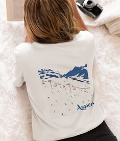 Introducing our Aspen Vintage-Inspired Tee, a timeless ode to the rustic charm and mountain allure of Aspen.  Featuring a vintage-inspired design, this tee effortlessly captures the essence of classic Aspen style. With its retro graphics and laid-back vibe, this unisex tee is perfect for everyone's outdoor adventures, après-ski gatherings, or simply lounging in cozy comfort.  Whether you're hitting the slopes or strolling through town, this tee is a must-have addition to your mountain trip.  Embrace the spirit of Aspen with our vintage-inspired tee and let your style soar to new heights. The unisex soft-style t-shirt puts a new spin on casual comfort. Made from very soft materials, this tee is 100% cotton for solid colors. Heather colors and sports grey include polyester. The shoulders hav Ski Decorations, Aspen Style, Ski Shirt, Aspen Ski, Mountain Graphic Tee, Mountain Trip, Ski Shirts, Retro Graphics, Ski Fashion