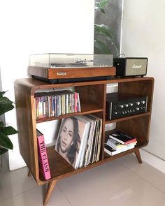 an old record player is sitting on top of a shelf with books, cds and records