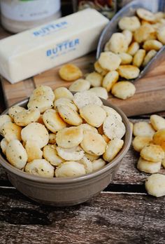 two bowls filled with small pieces of food on top of a wooden table next to butter cubes