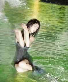 a woman is sitting in the water with her hands behind her head