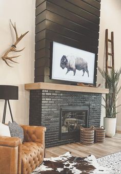 a living room with a couch, chair and television mounted on the wall above a fireplace