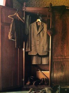 a suit and tie are hanging on a coat rack in a closet with other clothes