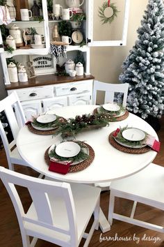 a dining room table set for christmas with plates and place settings on it, surrounded by holiday decorations