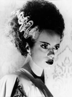 a black and white photo of a woman with curly hair in an old fashion hairstyle