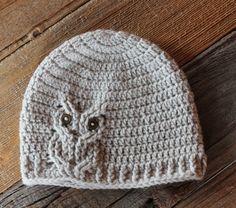 a crocheted hat with a button on the front sits on a wooden surface