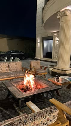 a fire pit sitting in the middle of a patio next to wooden benches and tables