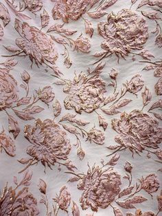 pink and gold embroidered fabric with large flowers on white background, closeup view from above