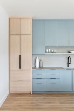 a kitchen with light blue cabinets and wooden floors